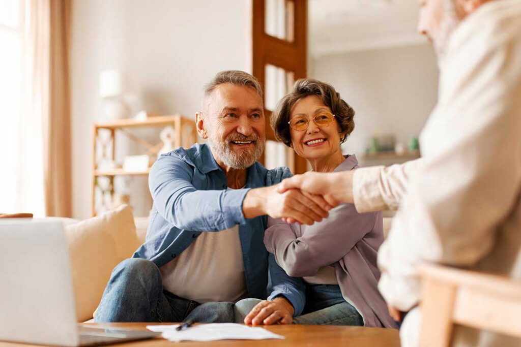 An older couple reviewing insurance documents together at their kitchen table with a notepad and coffee.